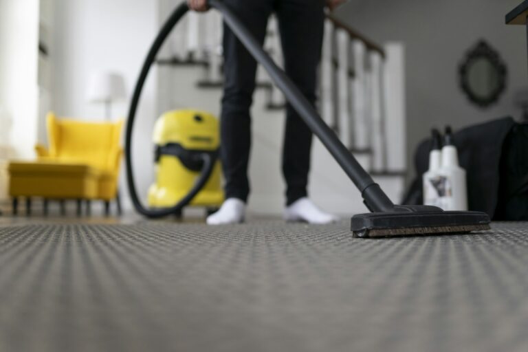 Man vacuuming the carpet in the room. House cleaning process